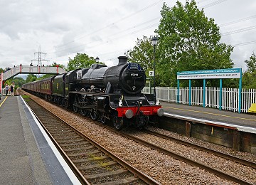 Steam train passing long station name at Llanfairpwll on Anglesey